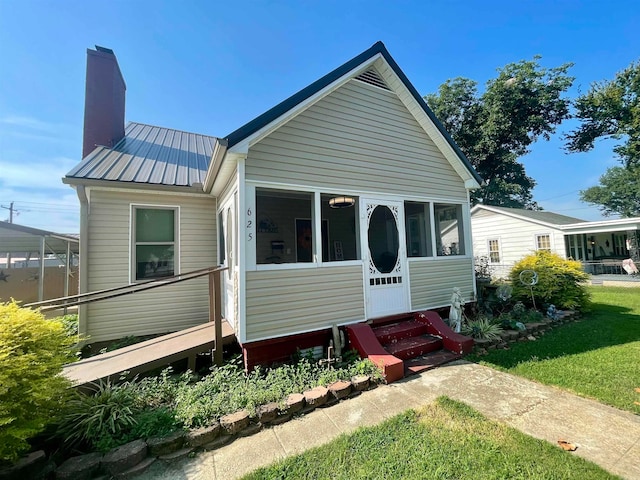 rear view of property with a lawn and a sunroom