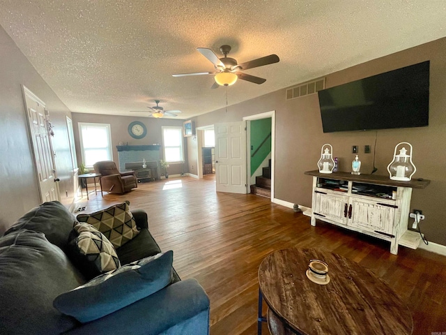 living room featuring a textured ceiling, ceiling fan, hardwood / wood-style flooring, and a fireplace