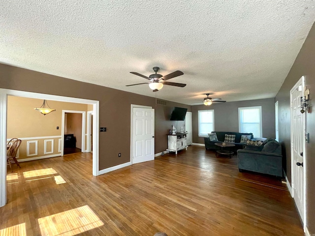 unfurnished living room with a textured ceiling, dark wood-type flooring, and ceiling fan