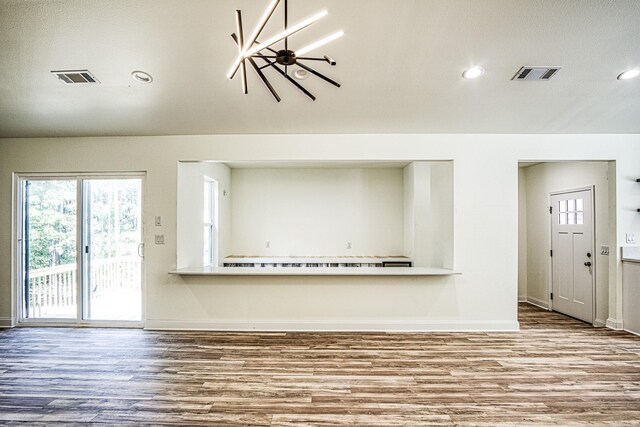 unfurnished living room with wood-type flooring and an inviting chandelier