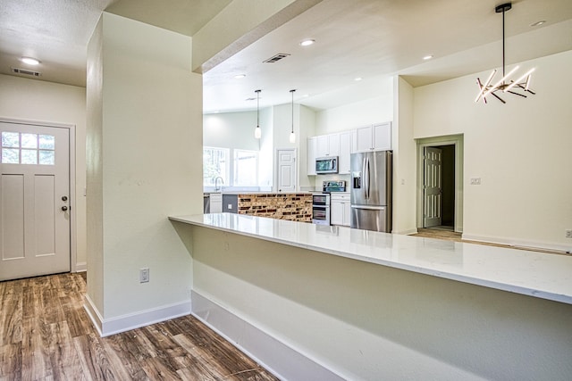 kitchen featuring a peninsula, appliances with stainless steel finishes, wood finished floors, and visible vents