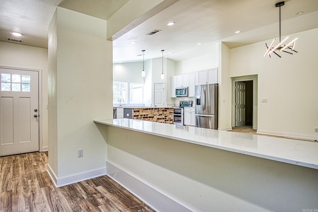 kitchen featuring appliances with stainless steel finishes, a healthy amount of sunlight, white cabinets, and dark hardwood / wood-style floors