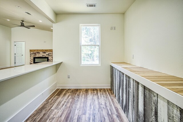 interior space with baseboards, visible vents, ceiling fan, wood finished floors, and a fireplace