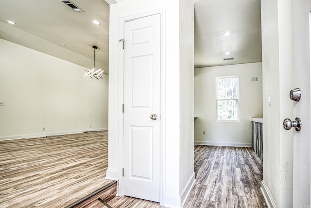 hallway featuring hardwood / wood-style floors and an inviting chandelier