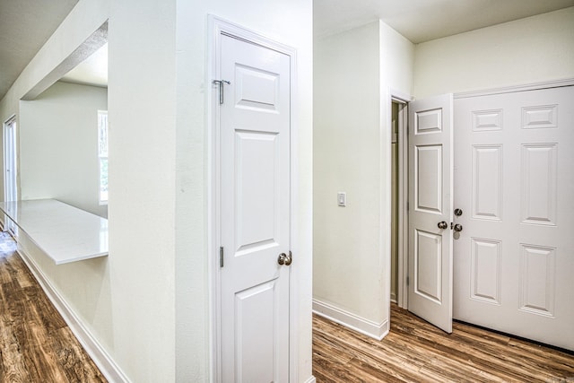 corridor with dark wood finished floors and baseboards