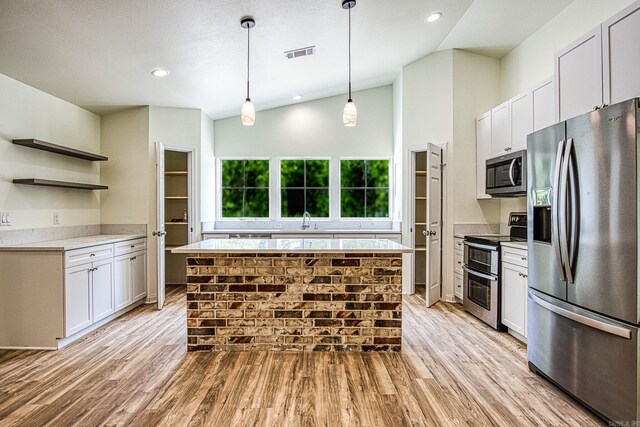 kitchen featuring light wood-type flooring, stainless steel appliances, a center island, sink, and lofted ceiling