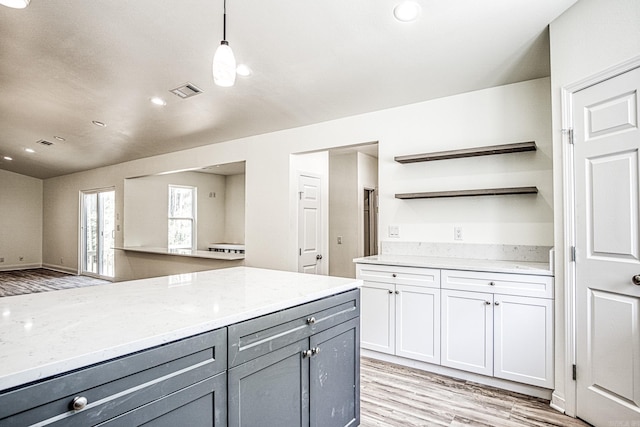 kitchen with light stone countertops, pendant lighting, and light hardwood / wood-style floors