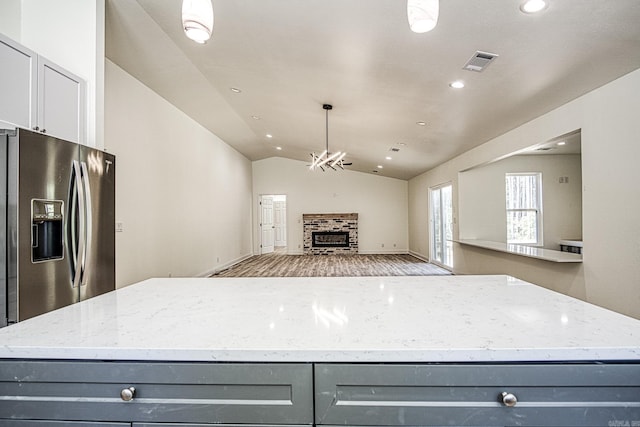 kitchen with pendant lighting, stainless steel fridge with ice dispenser, lofted ceiling, gray cabinetry, and light hardwood / wood-style floors