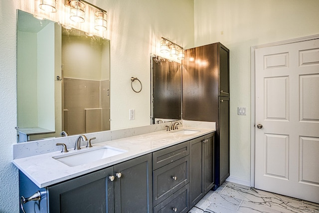 full bath with marble finish floor, a sink, baseboards, and double vanity