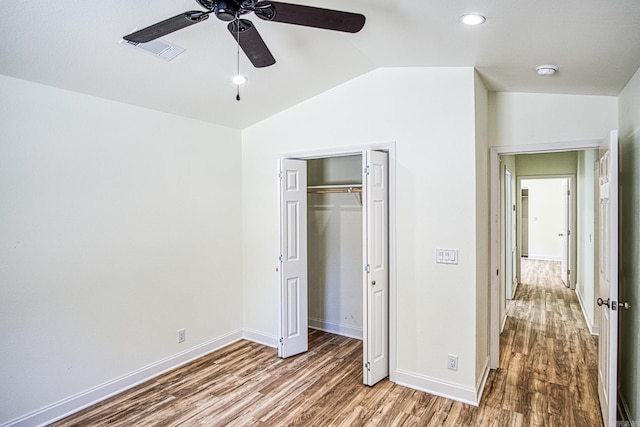 unfurnished bedroom featuring vaulted ceiling, hardwood / wood-style floors, ceiling fan, and a closet