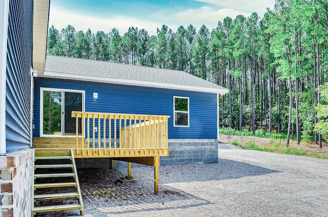 exterior space featuring driveway, a deck, and roof with shingles