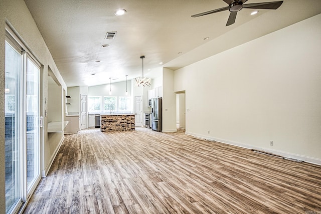 unfurnished living room with lofted ceiling, ceiling fan, light wood finished floors, and visible vents