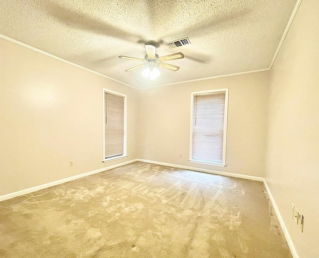 empty room with carpet, visible vents, ornamental molding, a ceiling fan, and baseboards