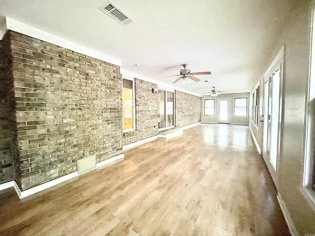 unfurnished living room featuring brick wall, visible vents, and wood finished floors