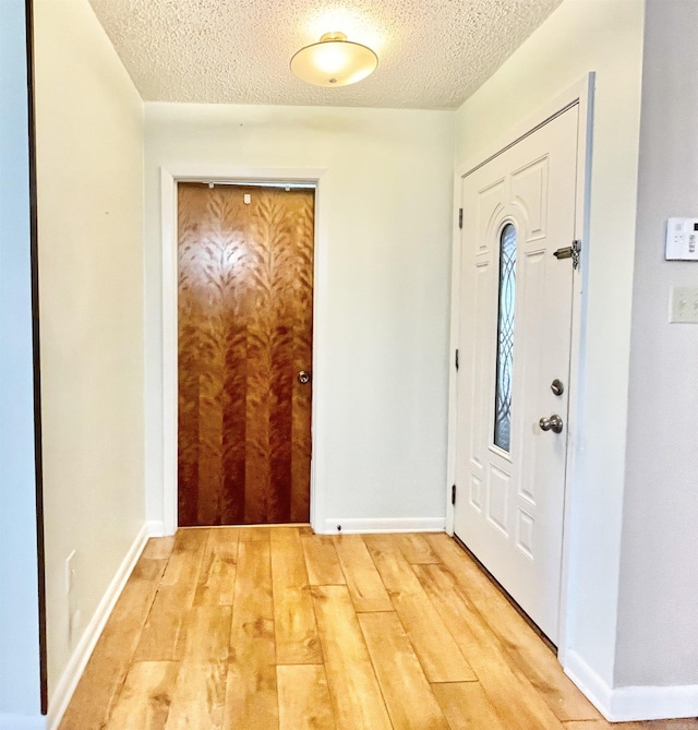 entrance foyer featuring baseboards, light wood-style flooring, and a textured ceiling