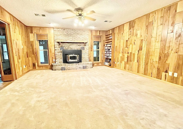 unfurnished living room with visible vents, wooden walls, and a textured ceiling