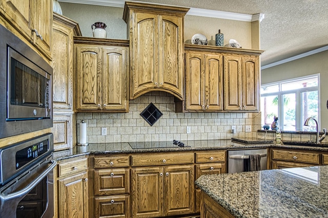 kitchen with a textured ceiling, stainless steel appliances, sink, and dark stone counters