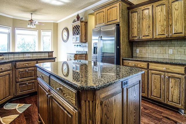 kitchen with dark hardwood / wood-style floors, stainless steel fridge, tasteful backsplash, a center island, and ceiling fan