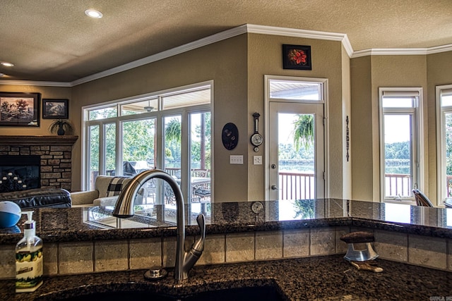 interior space with crown molding, a textured ceiling, a fireplace, and sink