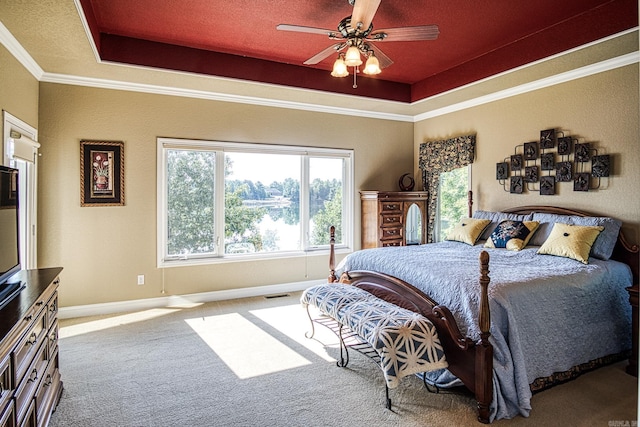 bedroom with crown molding, ceiling fan, carpet floors, and a tray ceiling