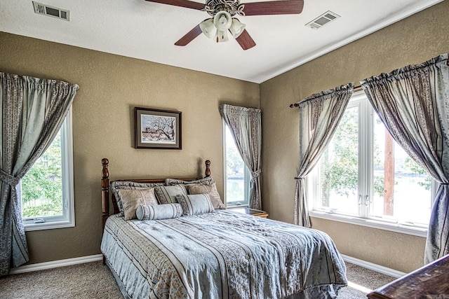 carpeted bedroom featuring multiple windows and ceiling fan