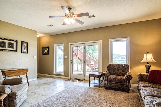 living room featuring a textured ceiling, ceiling fan, and light tile patterned floors