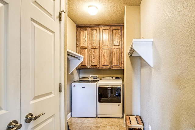 laundry room featuring cabinets, washer and clothes dryer, and a textured ceiling