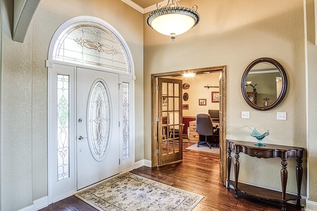 foyer entrance with dark wood-type flooring and crown molding