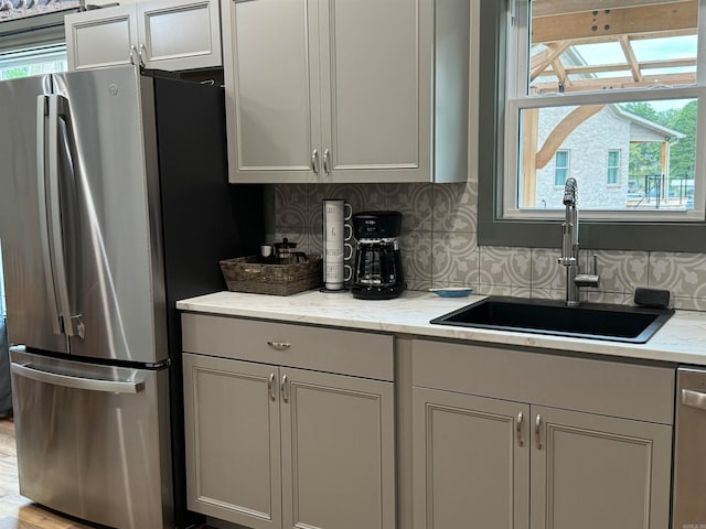 kitchen featuring light stone counters, sink, appliances with stainless steel finishes, and tasteful backsplash