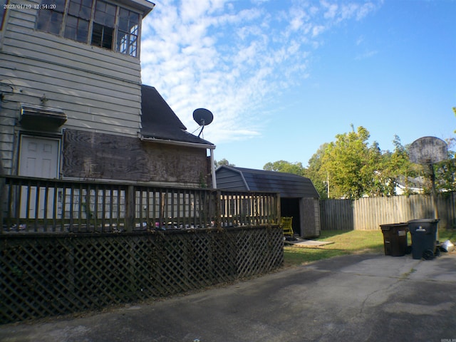 view of property exterior with a deck and a storage unit