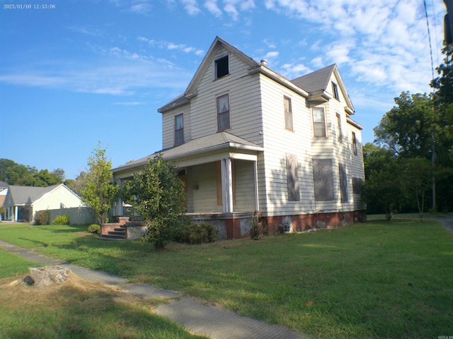 view of side of property with covered porch and a lawn