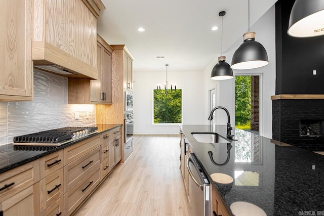 kitchen with appliances with stainless steel finishes, plenty of natural light, decorative light fixtures, and sink