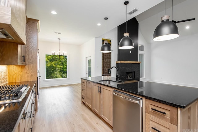 kitchen with appliances with stainless steel finishes, tasteful backsplash, hanging light fixtures, sink, and light wood-type flooring