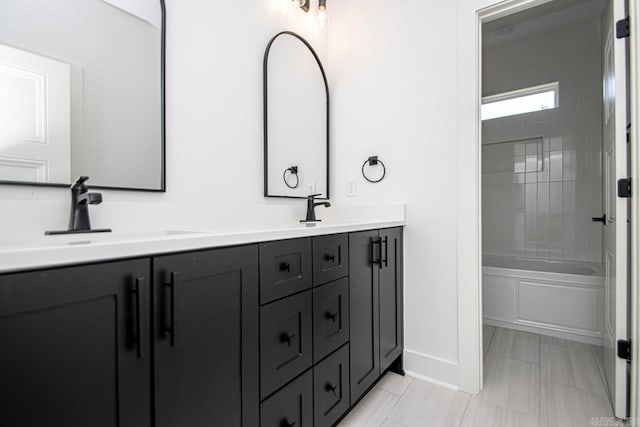 bathroom featuring tile patterned flooring, tiled shower / bath, and vanity