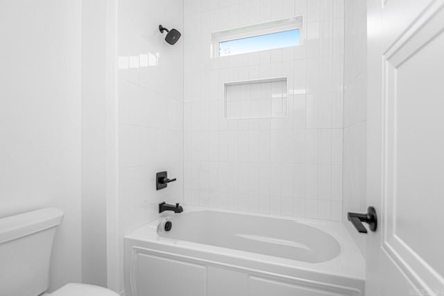 bathroom with toilet and tiled shower / bath combo