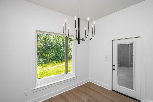 unfurnished dining area with hardwood / wood-style flooring, plenty of natural light, and an inviting chandelier