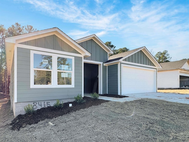 view of front of property with a garage, roof with shingles, board and batten siding, and an outbuilding