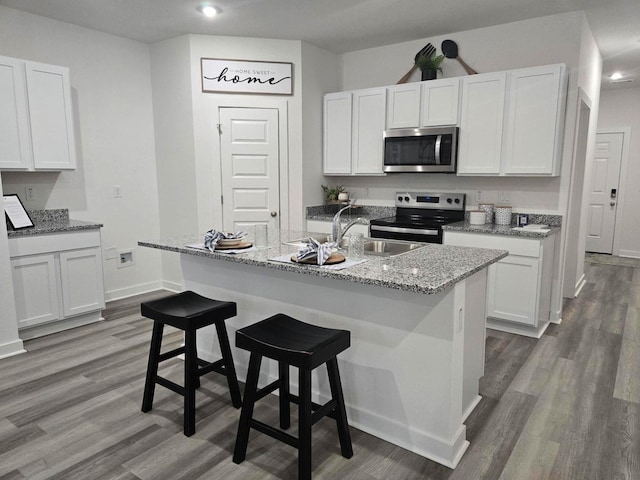 kitchen with white cabinetry, wood finished floors, baseboards, and appliances with stainless steel finishes