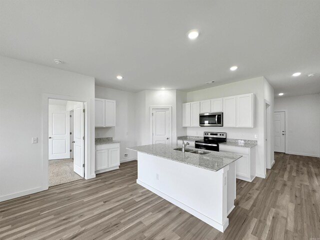 kitchen with white cabinets, appliances with stainless steel finishes, a center island with sink, and sink