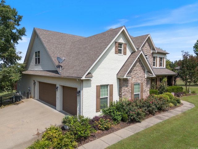24 W Jericho Dr, Greenbrier, AR 72058 - view of front facade featuring stone siding, concrete driveway, roof with shingles, and brick siding