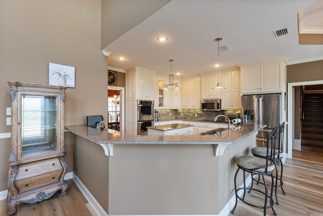 24 W Jericho Dr, Greenbrier, AR 72058 - kitchen with stainless steel appliances, visible vents, a breakfast bar area, and light stone countertops