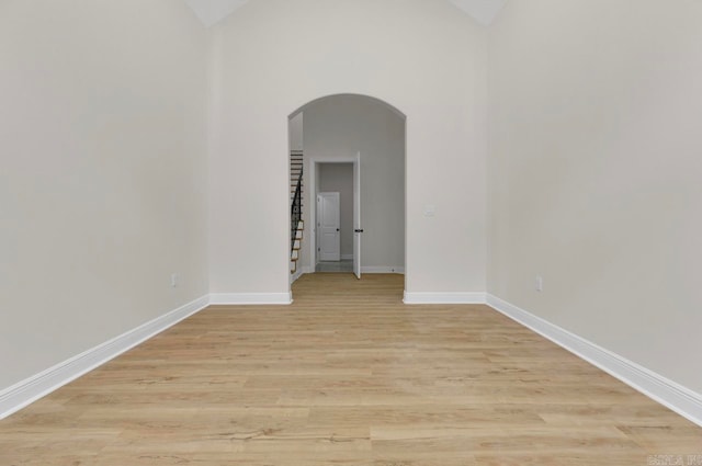 spare room featuring lofted ceiling and light hardwood / wood-style floors