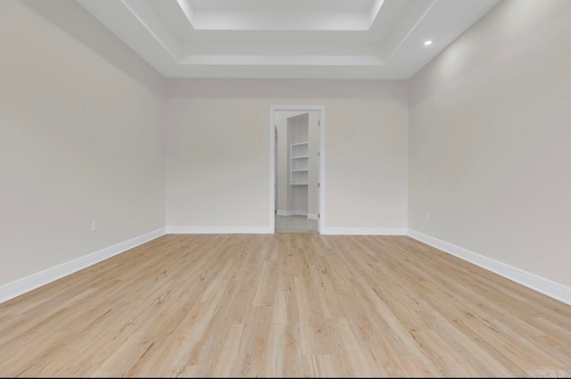 empty room featuring light wood-type flooring and a tray ceiling