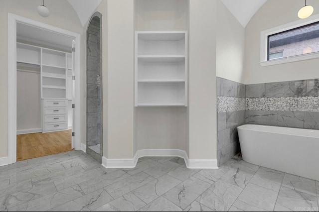 bathroom featuring built in shelves, independent shower and bath, tile walls, and vaulted ceiling