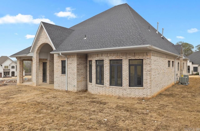 rear view of property with a yard and central air condition unit