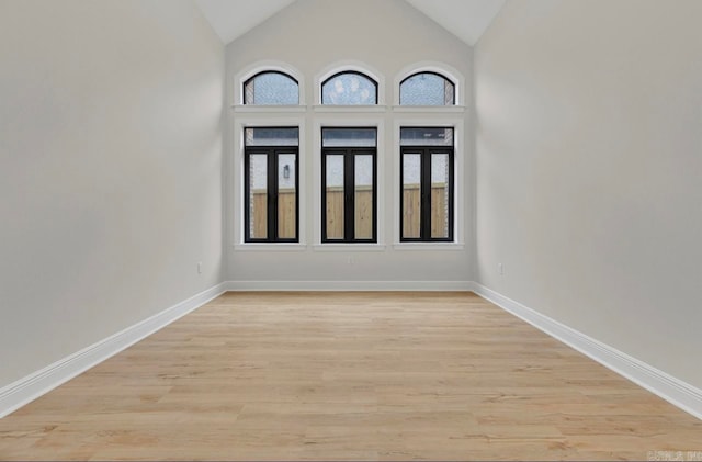 empty room with light wood-type flooring and high vaulted ceiling