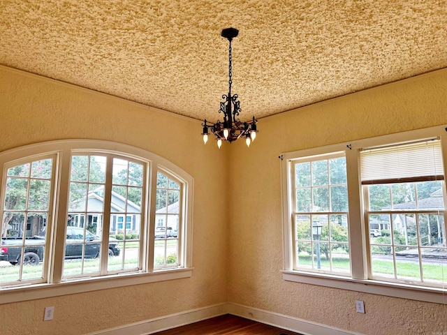 empty room with a healthy amount of sunlight, an inviting chandelier, and hardwood / wood-style floors