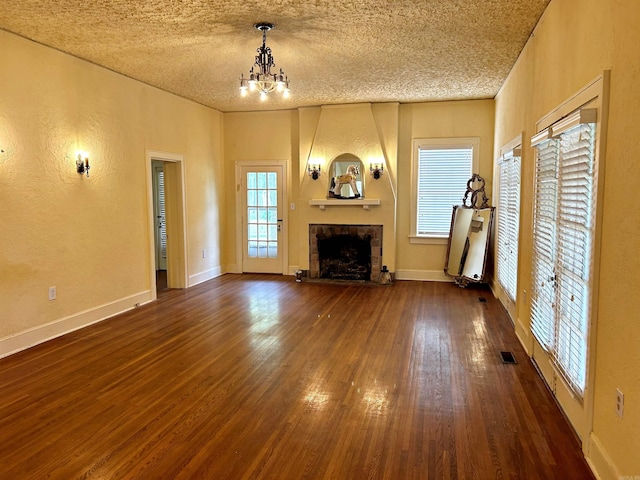 unfurnished living room featuring dark hardwood / wood-style flooring, a notable chandelier, and a textured ceiling