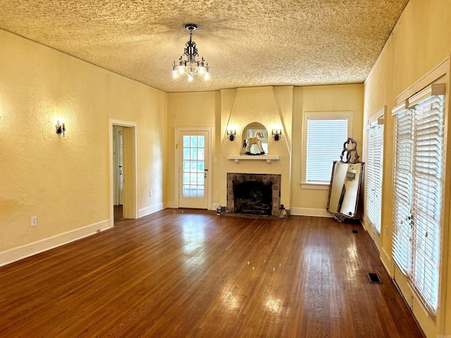 unfurnished living room with a textured ceiling, dark hardwood / wood-style floors, and a chandelier