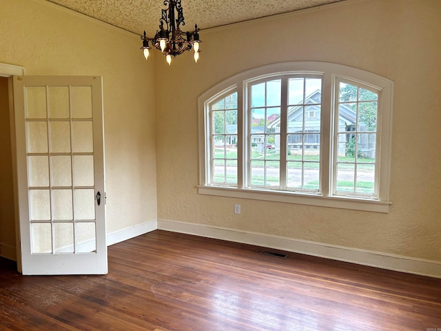 unfurnished room featuring dark hardwood / wood-style flooring, a notable chandelier, and a textured ceiling